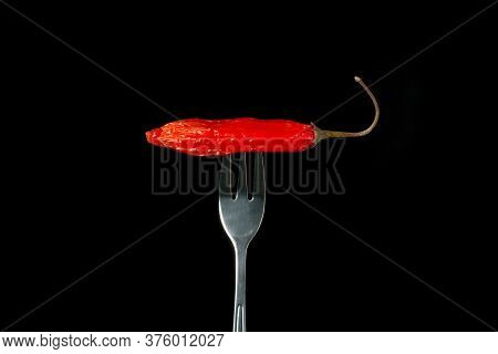 Hot Chili Pepper Pricked On A Fork Isolated On Black Background.