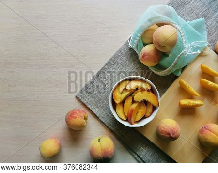 Juicy Sliced Peaches In A Plate, Next To Whole Peaches In A Reusable Bag On Burlap, Photo With Copy 