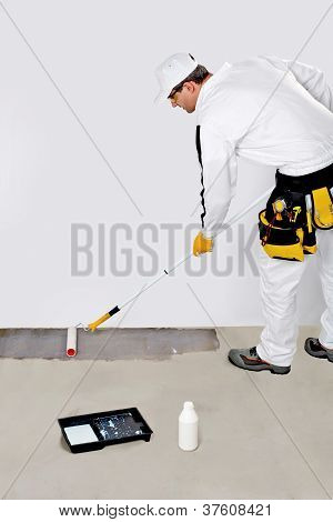 Trabalhador de pintura com Primer piso de concreto para impermeabilização