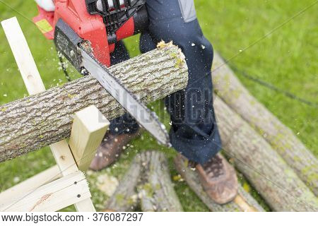 Electric Saw In Action Cutting Wood. Man Cutting Tree Trunk Into Logs With Saw In Motion. Close Up O