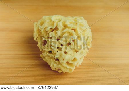 Top View Of Natural Sea Bath Cleaning Yellow Sponge For Washing On Wooden Table Background, Close-up