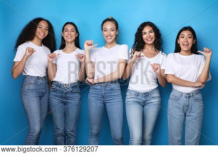 Choose Me. Diverse Girls Pointing At Themselves Smiling To Camera Posing In Studio Over Blue Backgro