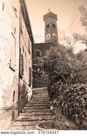 Old street and bell tower in Santarcangelo di Romagna town, Rimini province, Italy. Sepia toned black and white photography, vintage style