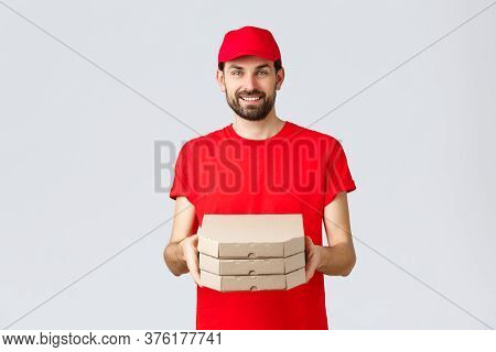 Food Delivery, Quarantine, Stay Home And Order Online Concept. Smiling Nice Bearded Courier In Red U