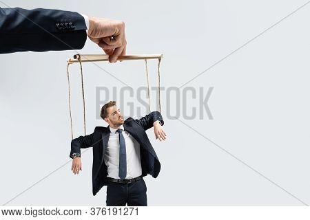 Cropped View Of Puppeteer Holding Businessman Marionette On Strings Isolated On Grey