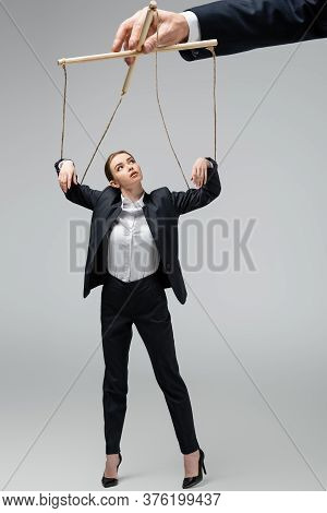 Cropped View Of Puppeteer Holding Businesswoman Marionette On Strings Isolated On Grey