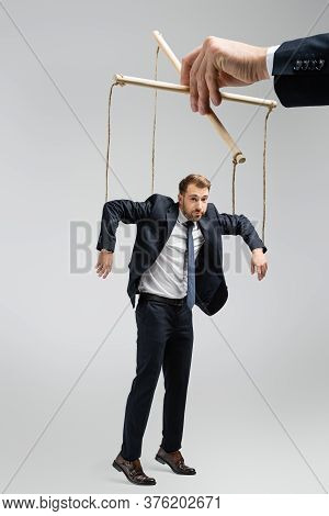 Cropped View Of Puppeteer Holding Businessman Marionette On Strings Isolated On Grey