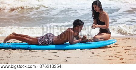 Blur Motion Of Young Handsome Man Teaching Beauty Lady For Basic Patter Of Surfing,on The Beach