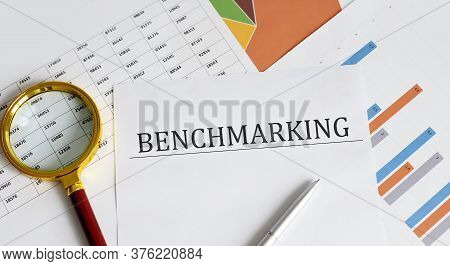 Text Benchmarking Is Written On A Paper With A Pen And A Magnifying Glass On The Table. Business Con