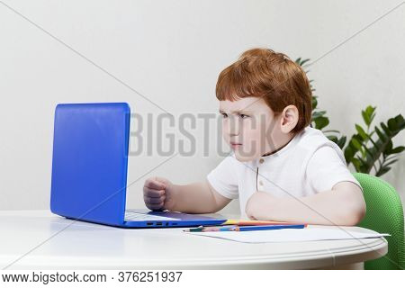 A Boy Looks At Information In A Blue Laptop While Learning Over The Internet, Close Up