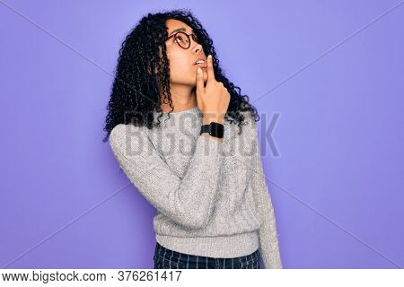 Young african american woman wearing casual sweater and glasses over purple background Thinking worried about a question, concerned and nervous with hand on chin