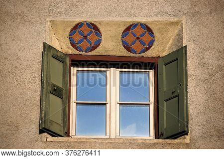 Old Wooden Window On A Wall With Decorations In The Ancient Village Of Guarda, Scuol Municipality, E