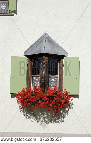 Old And Small Balcony With Wooden Windows And Red Geraniums, Village Of Zuoz, Tourist Resort In Enga