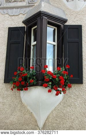 Old Balcony With Wooden Windows And Red Geraniums In The Ancient Village Of Ardez, Scuol Municipalit