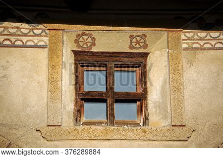 Old Wooden Window On A Wall With Decorations In The Ancient Village Of Guarda, Scuol Municipality, E