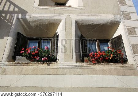 Old Wooden Windows With Potted Flowers And Decorations In The Ancient Village Of Ardez, Scuol Munici