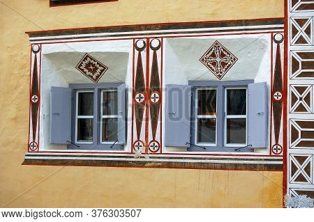 House With Wooden Windows And Geometric Decorations On The Wall In The Ancient Village Of Ardez, Scu
