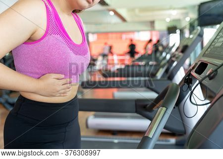 A Woman Feeling Exhausted And Suffering From Stomach Side Pain And Injury While Running On Treadmill