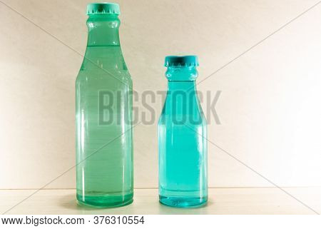 Colored Glass Bottles With Natural Water On Light And Illuminated Background
