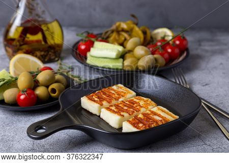 Grilled Haloumi Cheese On A Black Pan With Olives, Tomatoes, Cucumbers And Pepperoni. Close-up.