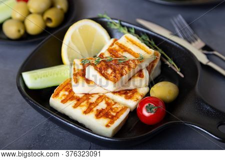Grilled Haloumi Cheese On A Black Pan With Olives, Tomatoes, Cucumbers And Pepperoni. Close-up.