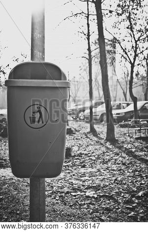 Vertical Black And White Shot To A Dumpster Mounted On Pillar With Recycle Symbol On It
