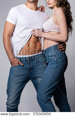 Cropped View Of Woman Touching White T-shirt Of Muscular Boyfriend Standing With Hand In Pocket Isol