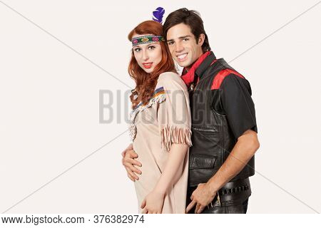 Portrait of young couple in old-fashioned costumes smiling against gray background