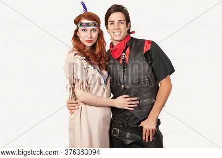 Portrait of young couple in old-fashioned costumes smiling against gray background