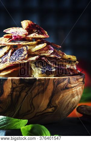 Chips From Purple And Red Potatoes In Wooden Bowl On Background Of Vegetables, Selective Focus