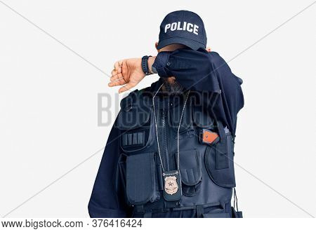 Young handsome man wearing police uniform covering eyes with arm, looking serious and sad. sightless, hiding and rejection concept 
