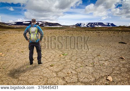 Hiker Man With Backpack Standing In Icelandic Desert Looking To Snow Mountain Thorisjokull And Ok Vu