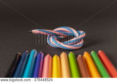 Flexible Pencil And A Set Of Colored Pencils On A Dark Background. Selective Focus