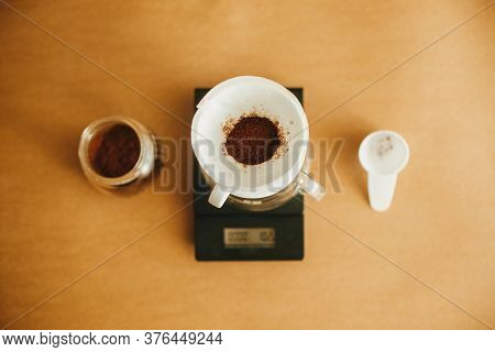 Drip Coffee Flat Lay. Grounded Coffee In Filter Pour Over On Scale And Glass Cup On Brown Background