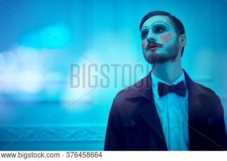 Art and fashion. Portrait of a young man with makeup in the style of the 20s in an elegant suit. Male mime artist. Studio portrait.