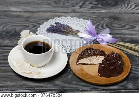 A Cup Of Black Coffee On A Saucer. Nearby Zephyr In Chocolate, Cut In Half, A Slice Is Visible. Zeph