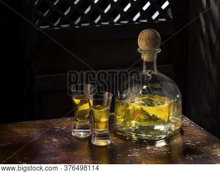 Close Up View Of Bottle Of Tequila Anejo And Glasses On Color Background