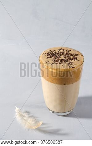 Korean Coffee Dalgon In A Glass Cup On A Gray Background. The Foam Is Sprinkled With Chocolate Chips