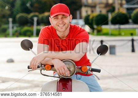 Smiling Driver Leant On Scooter. Young Guy, Dressed In Casual Clothes