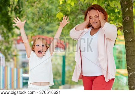 Family. Portrait Of A Worried Mother With A Cheerful Daughter In The Park. The Concept Of Childrens 