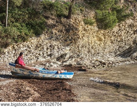 Hiker Woman Dreaming About Sailing, Boat On Bank Anchored In Stones And Colorful Pebles.