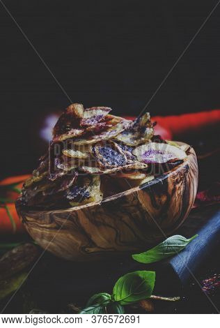 Chips From Purple And Red Potatoes In Wooden Bowl On Background Of Vegetables, Selective Focus