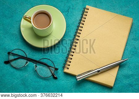 desktop flat lay with a blank spiral notebook, reading glassess and a cup of coffee, business and workspace concept