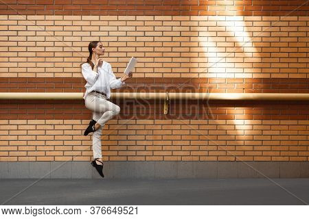 Scrolling Tablet. Jumping Young Woman In Front Of City Building Wall, On The Run In Jump High. Hurry