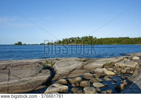 Clear Sky, Blue Water And Stones From Gabbro Diabase On The Shores Of Lake Ladoga.