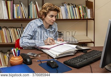 Image Of A Busy Woman Teleworking At Her Desk At The Home. Working At Home Became An Important Recom
