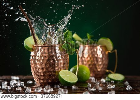 Famous splashing Moscow mule alcoholic cocktail in copper mugs, freeze motion effect.