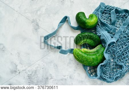 Trendy Ugly Vegetables. Fresh Ugly Cucumbers On A Concrete, Background In A String Bag. Imperfect Fo