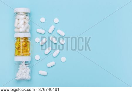 Three Packages With Various White Pills And Capcules On A Blue Background. Health Concept. Copy Spac
