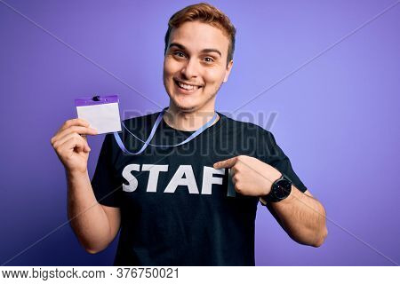 Young handsome redhead worker man wearing staff t-shirt uniform holding id card pass pointing finger to one self smiling happy and proud
